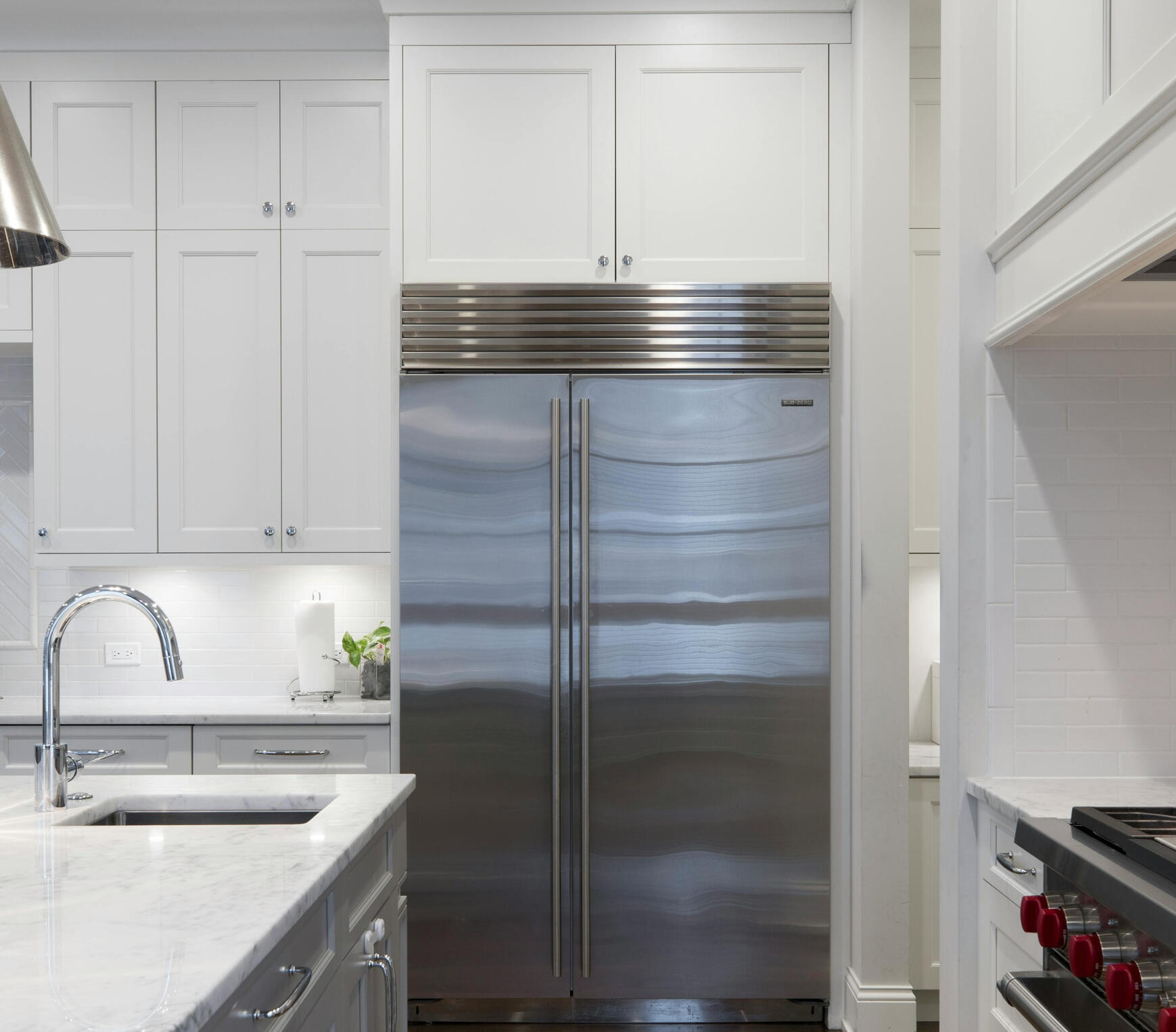 Modern kitchen with stainless steel double‑door fridge, white cabinetry, marble benchtop, and gas stove A bright modern kitchen featuring a stainless steel double‑door fridge, white cabinetry with silver handles, a marble benchtop, and a gas stove. This clean, practical layout showcases the quality renovation work provided by Sydney Budget Kitchens.