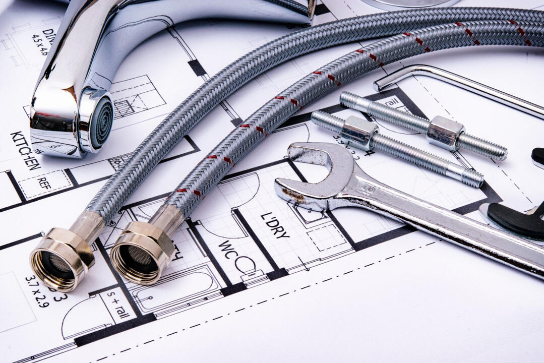 Plumbing fixtures, flexible water hoses, and renovation tools on architectural plans, representing full-service home renovation, bathroom remodeling, and construction projects in Sydney.