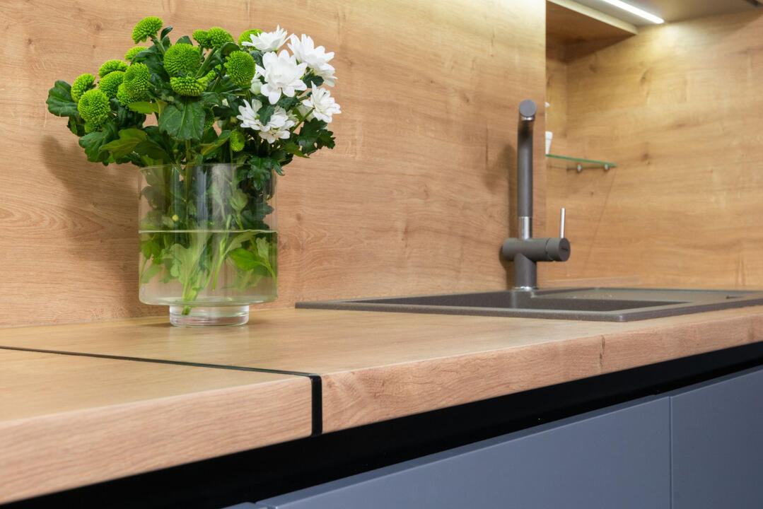 Kitchen Renovation Sydney | Benchtop, Cabinetry & Material Selection Contemporary kitchen renovation with a timber-look benchtop, black tapware, integrated sink, and custom cabinetry, showcasing kitchen design and material selection expertise in Sydney.