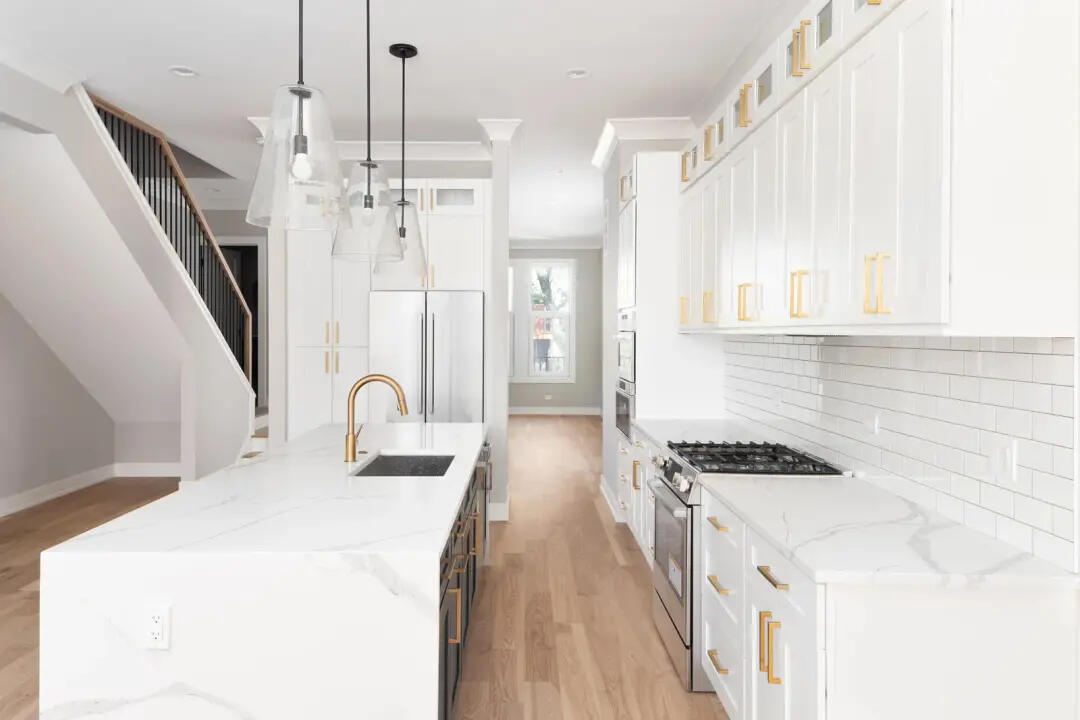 Luxury kitchen renovation with white shaker cabinets, marble-look benchtops, gold fixtures, pendant lighting, and timber floors, representing highly rated kitchen renovation projects in Sydney.
